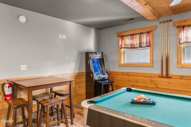 rec room featuring wooden walls, visible vents, wainscoting, wood finished floors, and beam ceiling