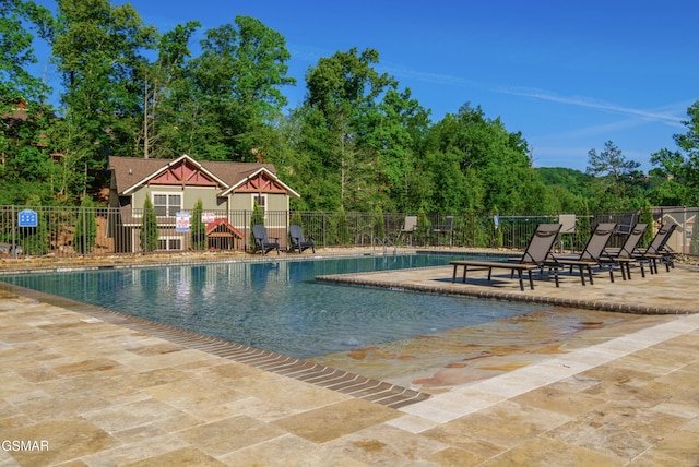 pool with a patio area and fence