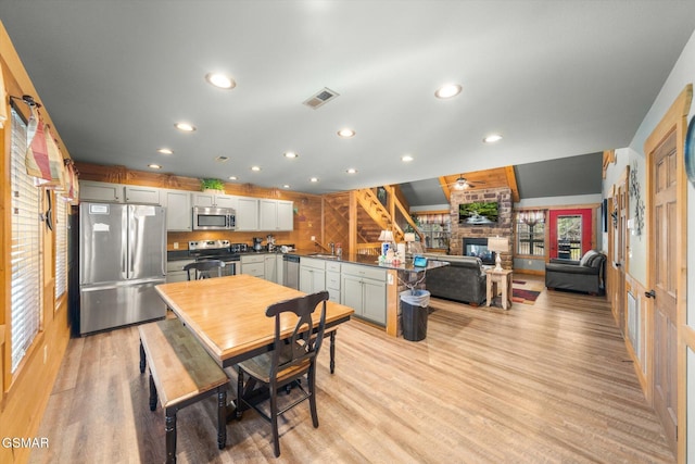 dining room featuring visible vents, a ceiling fan, light wood-style flooring, a fireplace, and recessed lighting