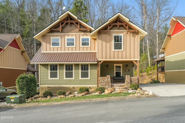 craftsman inspired home with metal roof, stone siding, board and batten siding, and driveway