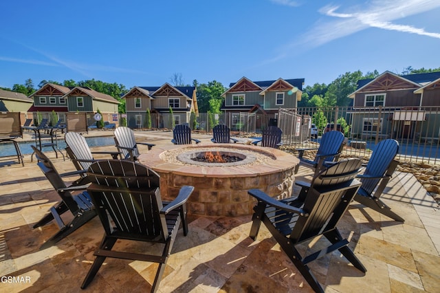 view of patio / terrace featuring an outdoor fire pit, fence, and a residential view