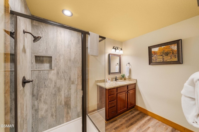 bathroom featuring a stall shower, baseboards, wood finished floors, and vanity