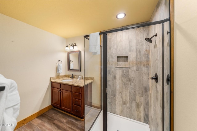 bathroom with baseboards, a shower stall, vanity, and wood finished floors