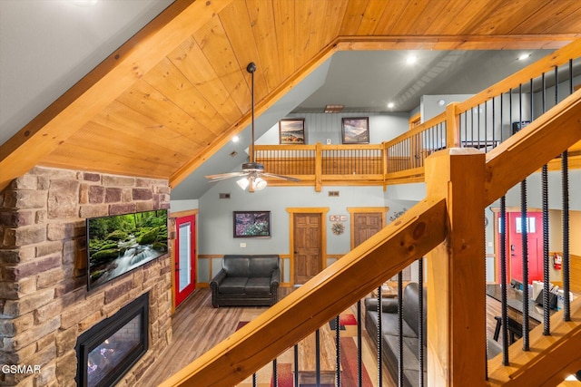 living area with a fireplace, wood finished floors, high vaulted ceiling, wooden ceiling, and stairs