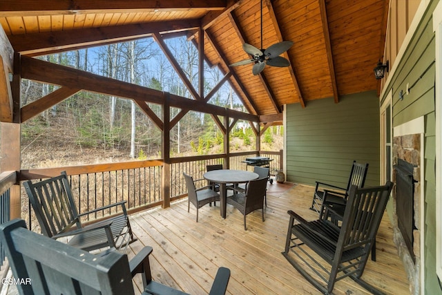 wooden deck with outdoor dining space and a ceiling fan