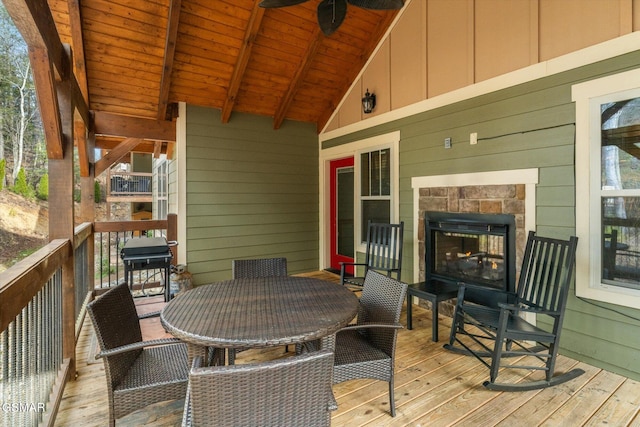 deck with a ceiling fan, an outdoor stone fireplace, and a grill