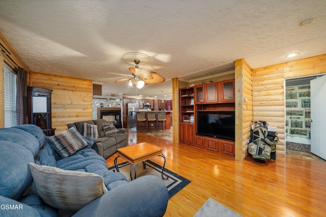 living room featuring log walls, light hardwood / wood-style floors, and a textured ceiling