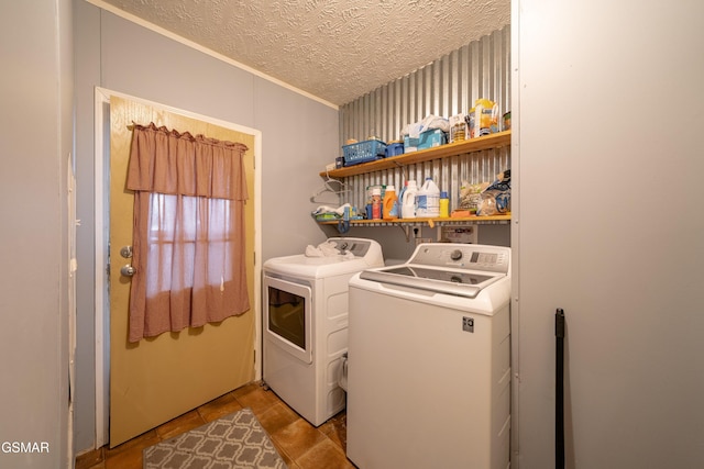 clothes washing area featuring light tile patterned flooring, washer and dryer, and a textured ceiling