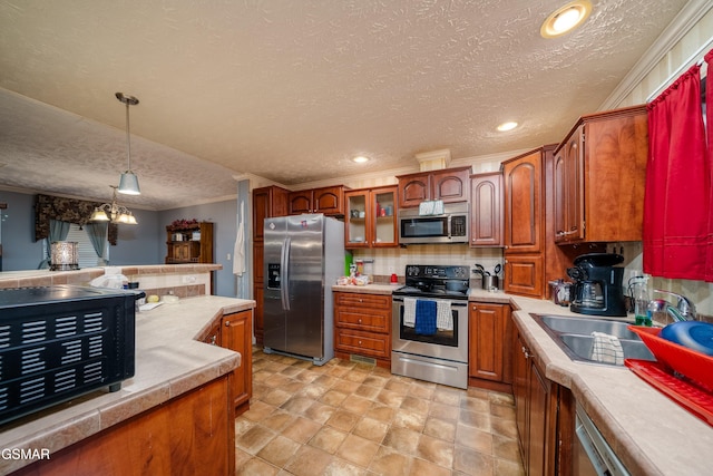 kitchen featuring sink, hanging light fixtures, a textured ceiling, ornamental molding, and appliances with stainless steel finishes