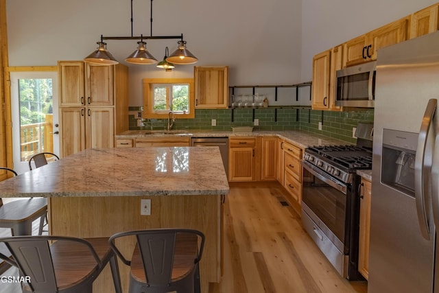 617 Davenport Rd, Gatlinburg, TN 37738 - kitchen featuring stainless steel appliances, a breakfast bar, light wood-style floors, decorative backsplash, and plenty of natural light