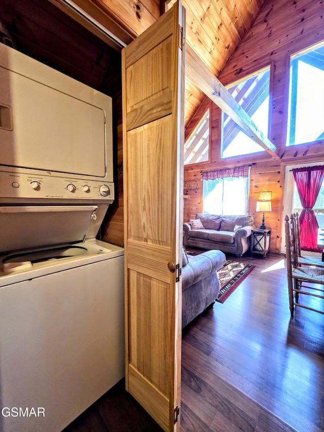 clothes washing area featuring dark wood-style floors, wooden walls, stacked washer / drying machine, wood ceiling, and laundry area