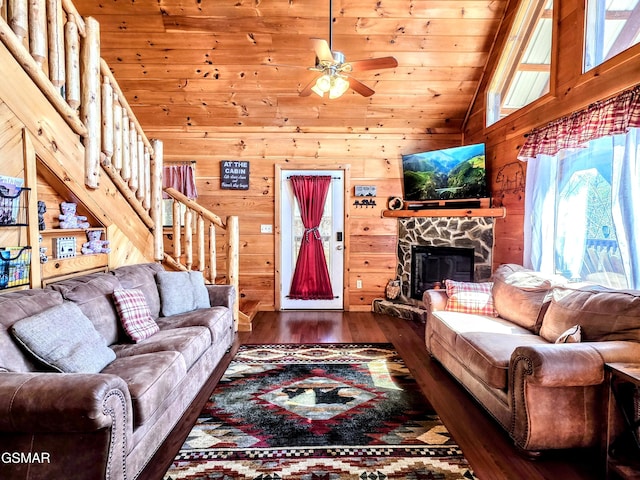 living area featuring high vaulted ceiling, wood finished floors, wood walls, a fireplace, and stairs