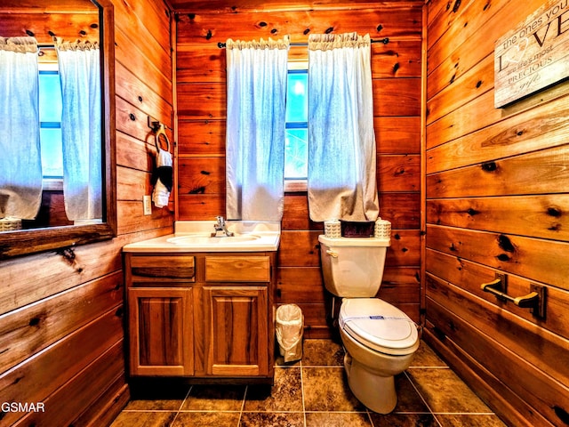 half bathroom with toilet, plenty of natural light, vanity, and wood walls