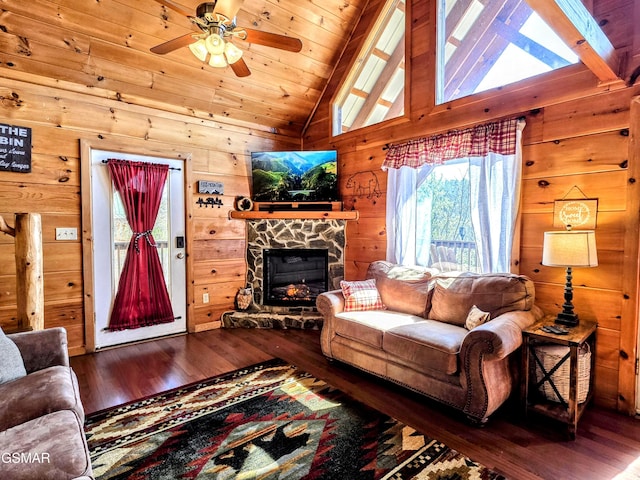 living area with ceiling fan, wood walls, wood ceiling, a stone fireplace, and hardwood / wood-style flooring