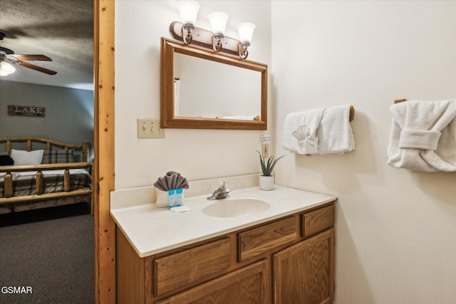 bathroom with ceiling fan, a textured ceiling, and vanity