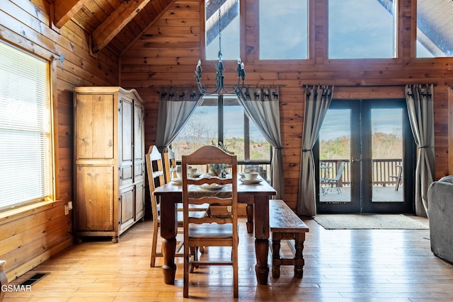 dining area featuring visible vents, french doors, wood walls, and beam ceiling