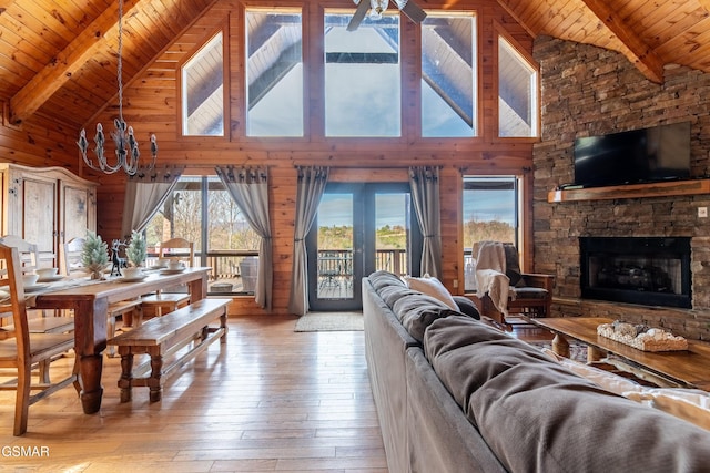 living room featuring wooden ceiling, wood-type flooring, a stone fireplace, a healthy amount of sunlight, and wood walls