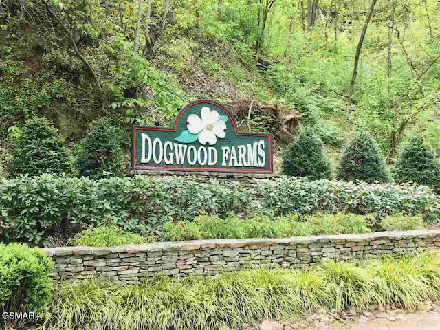 community / neighborhood sign featuring a wooded view