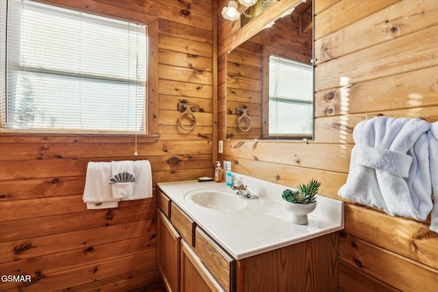 bathroom with wood walls, vanity, and a healthy amount of sunlight