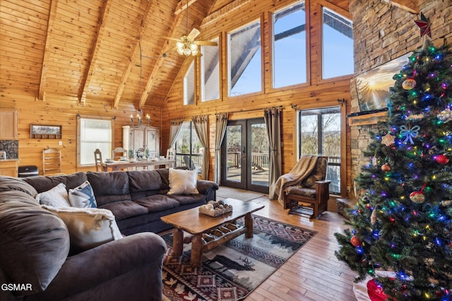 living room with beam ceiling, wood-type flooring, wooden walls, high vaulted ceiling, and wooden ceiling