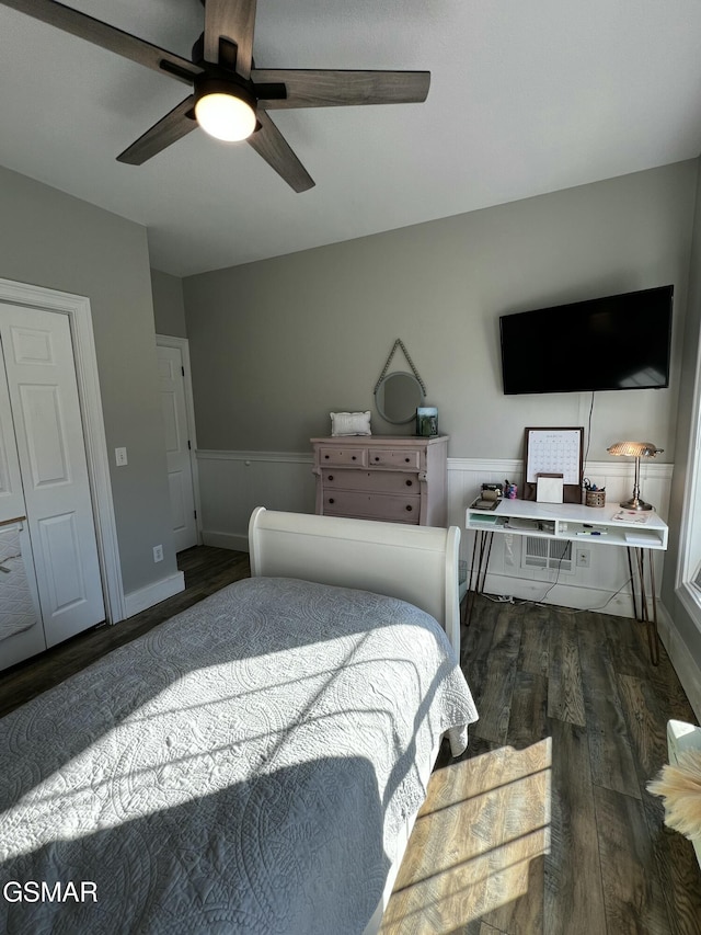 bedroom featuring a wainscoted wall, dark wood finished floors, and a ceiling fan