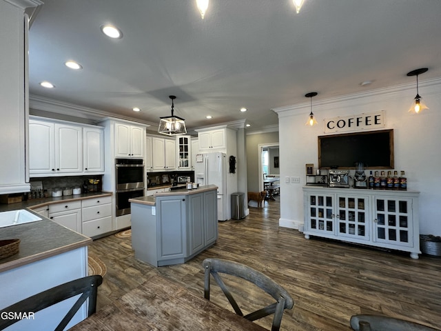 kitchen with dark countertops, white cabinets, decorative light fixtures, and white refrigerator with ice dispenser