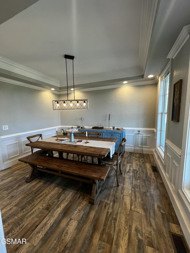 dining room with dark wood-type flooring, a wainscoted wall, visible vents, and crown molding