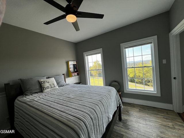 bedroom featuring wood finished floors, a ceiling fan, and baseboards