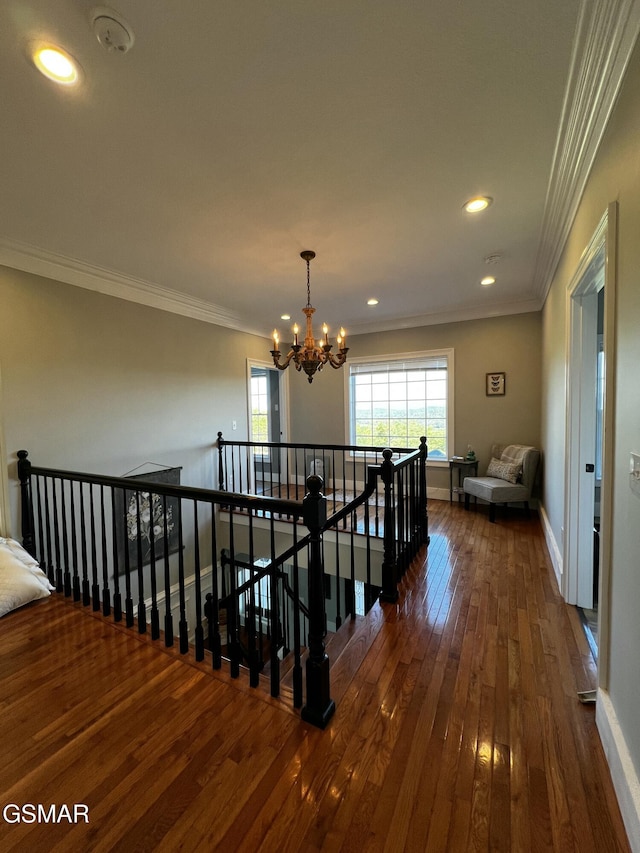 hallway featuring a notable chandelier, crown molding, dark wood-type flooring, an upstairs landing, and baseboards