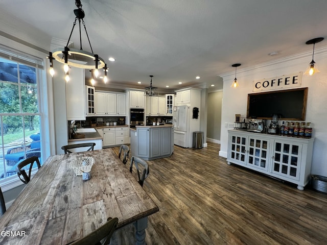 dining room featuring dark wood-type flooring, recessed lighting, crown molding, and baseboards