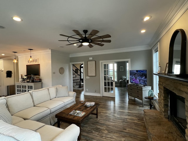 living room with a stone fireplace, dark wood-type flooring, stairway, and recessed lighting