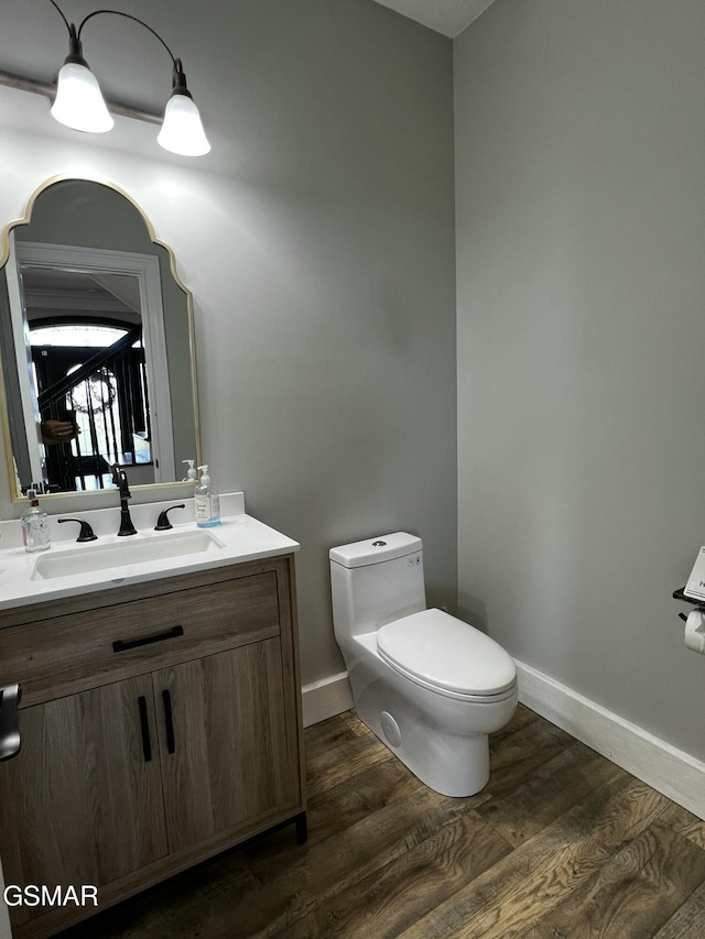 half bathroom featuring toilet, baseboards, wood finished floors, and vanity