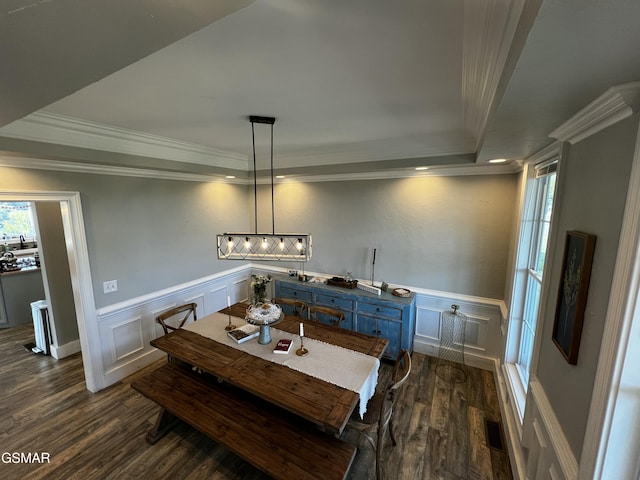 dining area with dark wood-style flooring, a raised ceiling, and crown molding