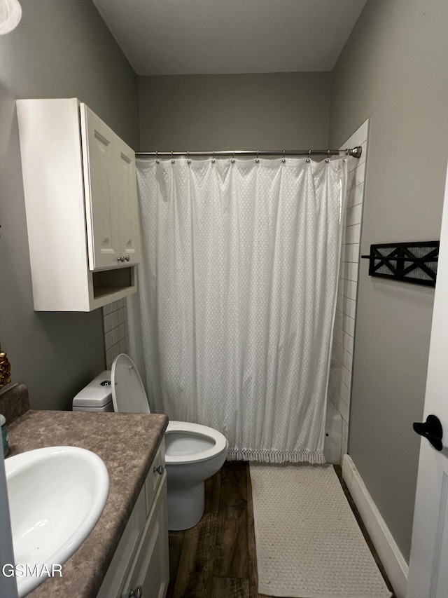 bathroom featuring curtained shower, toilet, vanity, wood finished floors, and baseboards