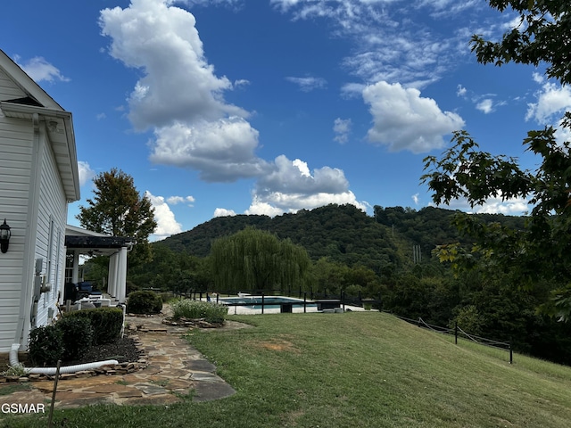 view of yard with a wooded view, a mountain view, and an outdoor pool