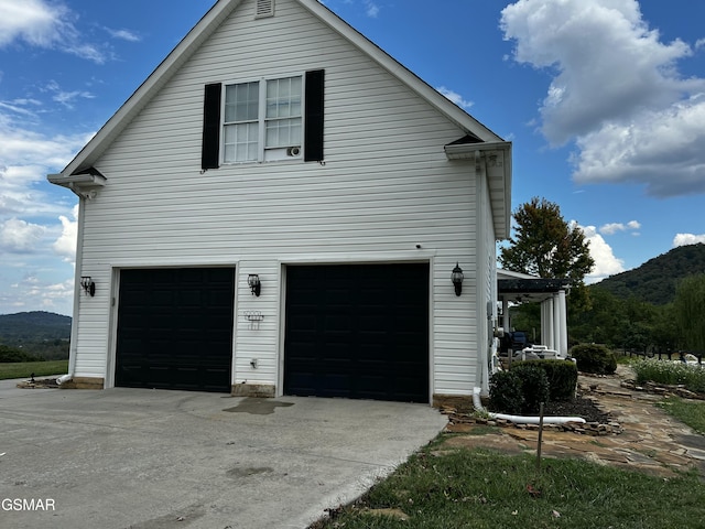 view of side of home with a garage, driveway, and a mountain view