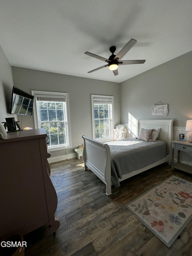 bedroom featuring dark wood-style flooring, a ceiling fan, and baseboards