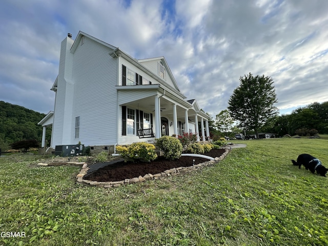 view of property exterior featuring a porch, a ceiling fan, a yard, crawl space, and a chimney