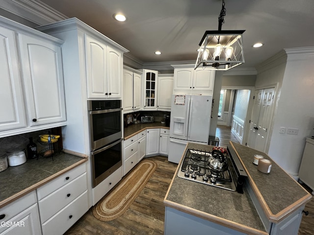 kitchen with appliances with stainless steel finishes, dark countertops, glass insert cabinets, and pendant lighting