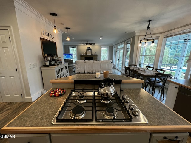 kitchen with pendant lighting, crown molding, dark countertops, and stainless steel gas stovetop