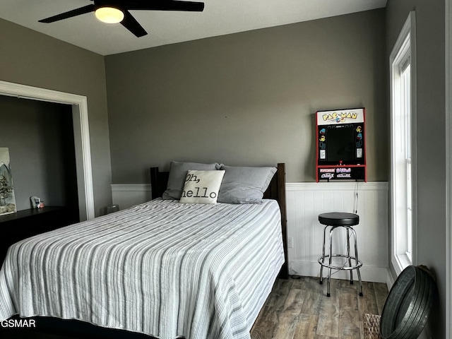 bedroom with wainscoting, ceiling fan, and wood finished floors