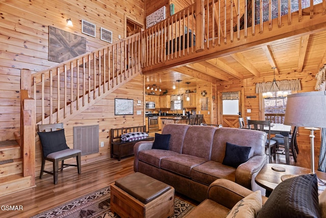 living room with wood walls, wood ceiling, an inviting chandelier, beamed ceiling, and a healthy amount of sunlight