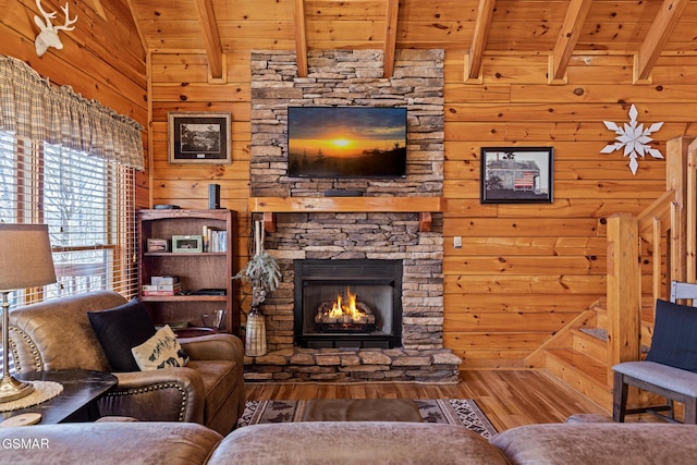 living room with a stone fireplace, lofted ceiling with beams, wooden ceiling, wooden walls, and hardwood / wood-style floors