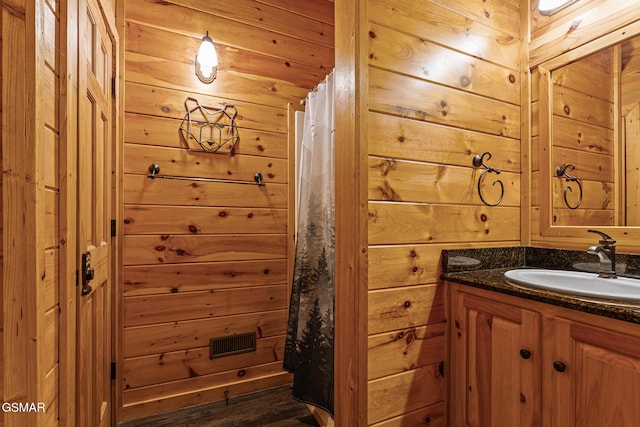 bathroom with a shower with curtain, vanity, wood-type flooring, and wood walls