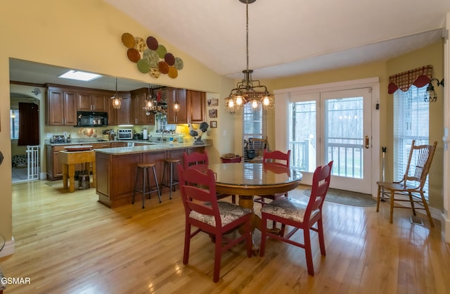 dining area featuring light wood-type flooring, lofted ceiling, and an inviting chandelier