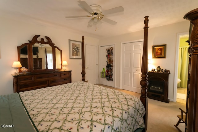 bedroom with multiple closets, ensuite bath, a ceiling fan, and light colored carpet