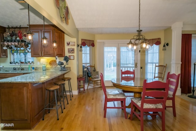 dining area with light wood-style floors, baseboards, and ornate columns