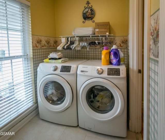 laundry area featuring light tile patterned floors, a wainscoted wall, laundry area, separate washer and dryer, and tile walls