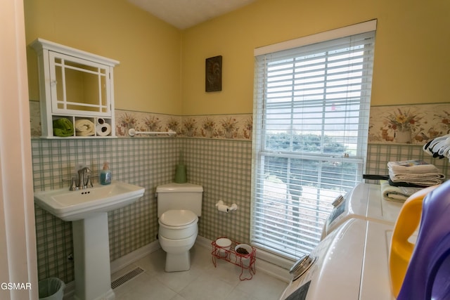 bathroom featuring a wainscoted wall, visible vents, toilet, a sink, and tile patterned floors