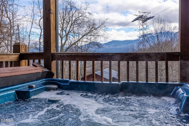 snow covered deck featuring a mountain view and a hot tub